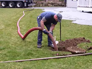 Septic pumping technician servicing a residential septic tank with a vacuum hose in Virginia Beach, VA